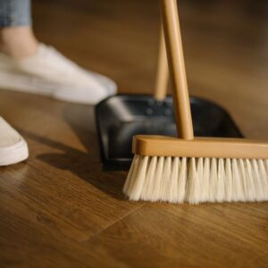 Person using a broom and dust pan to illustrate the housekeeping amenities offered at The Abbey of Olympus Retirement Living.
